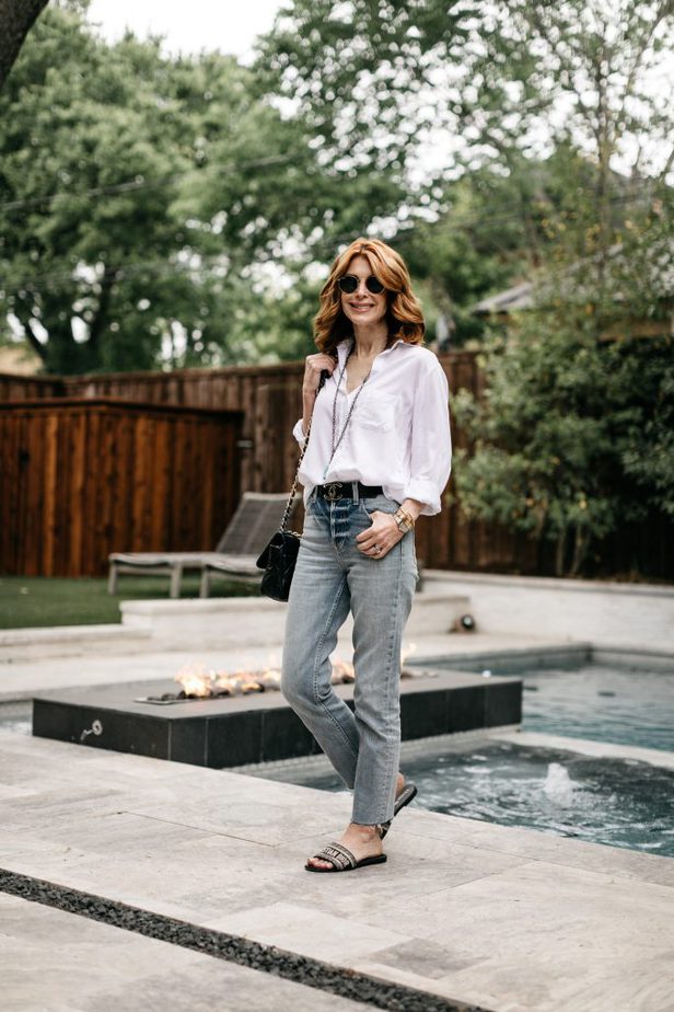 woman standing at the poolside wearing White Button-Down, jeans, and sunglasses
