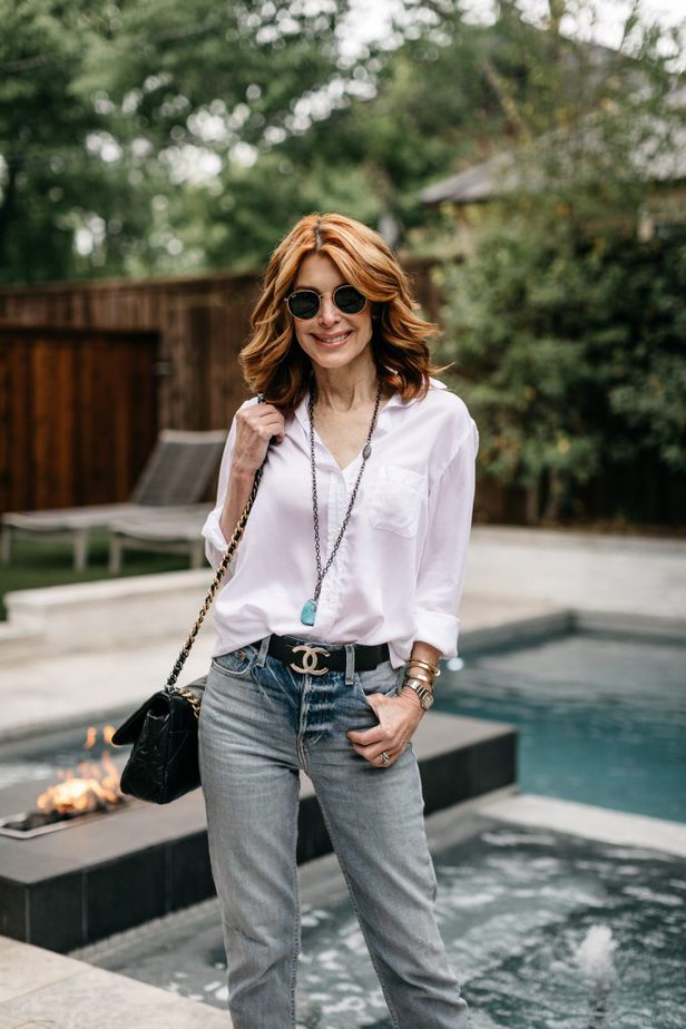 woman standing at the poolside wearing White Button-Down, jeans, and sunglasses