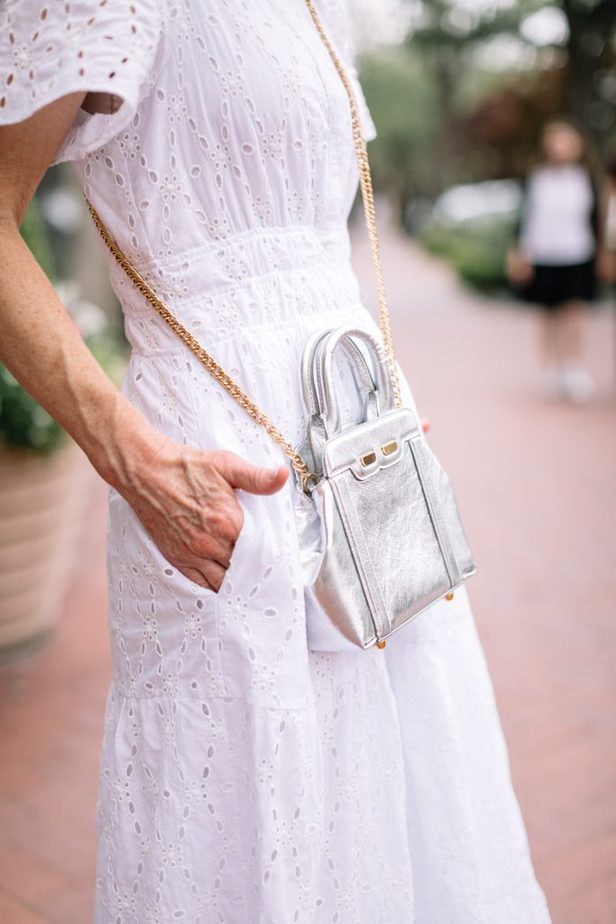 silver hand bag on white eyelet dress