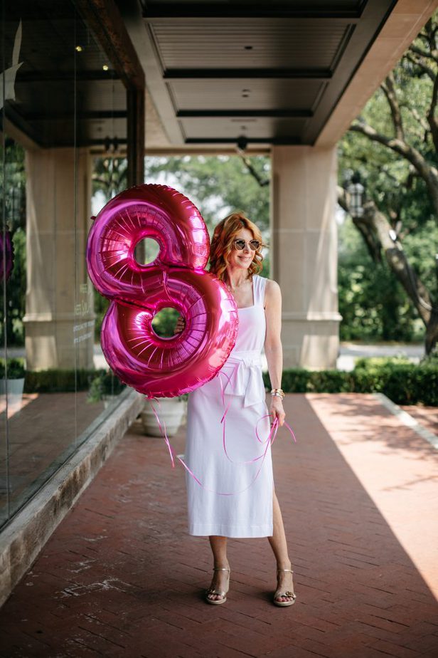 woman holding a pink number eight balloon