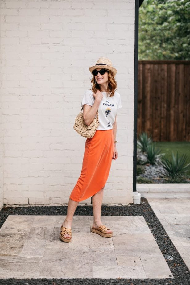 woman posing and wearing white top and orange skirt