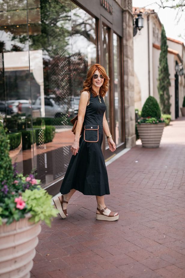 woman walking and wearing one of her black Summer Cotton Dresses from Staud  and platform sandals 