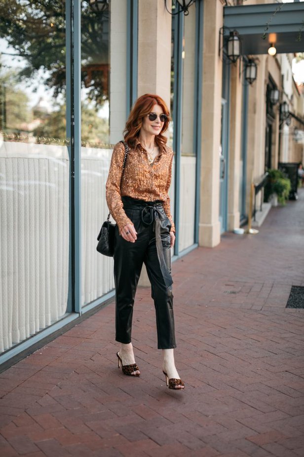 Dallas woman over 50 wearing black vegan leather paper bag waist pants with sequin top.